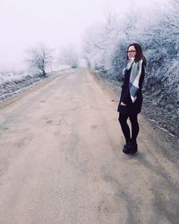 Full length portrait of woman standing on road during winter