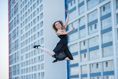 Woman jumping against buildings in city