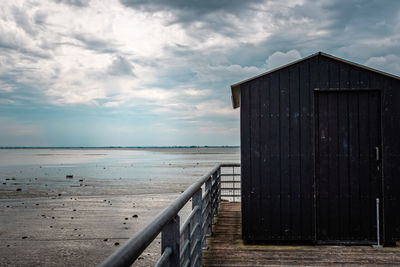 Wooden posts on beach against sky