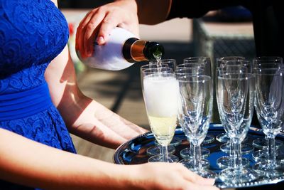 Midsection of woman serving champagne