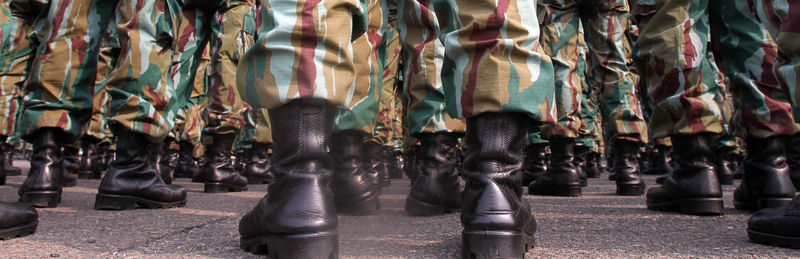 Low section of military soldiers marching on street