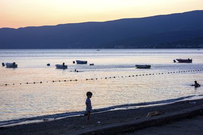 People on beach against sky during sunset