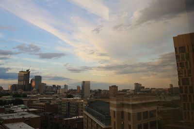 Modern buildings in city against sky during sunset