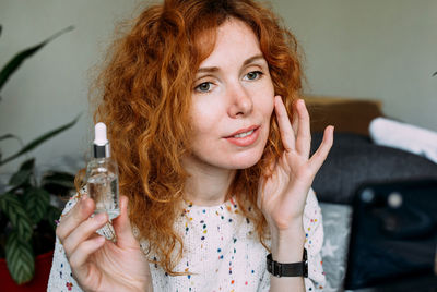 Portrait of young woman holding bottle