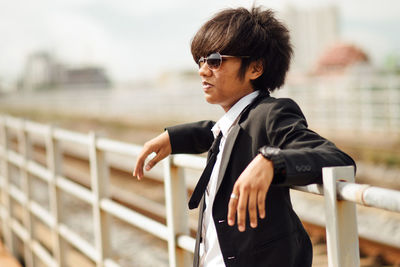 Side view of young man wearing sunglasses standing outdoors