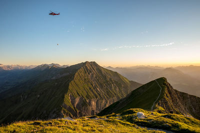 Scenic view of mountains with helicopter flying against sky