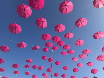 Low angle view of pink lanterns hanging against blue sky