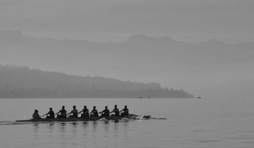 Rowing team in scull on lake during foggy weather