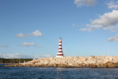 Lighthouse by sea against sky