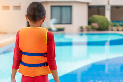 Rear view of boy standing in swimming pool
