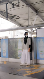 Full length portrait of young woman standing in corridor
