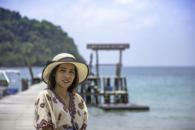 Portrait of woman on pier at sea against sky