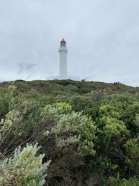 Lighthouse by street amidst buildings against sky