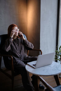 Young woman using mobile phone while sitting at cafe