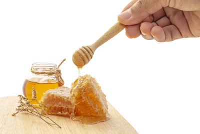 Close-up of hand holding ice cream against white background