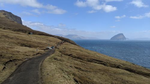 Scenic view of road by sea against sky