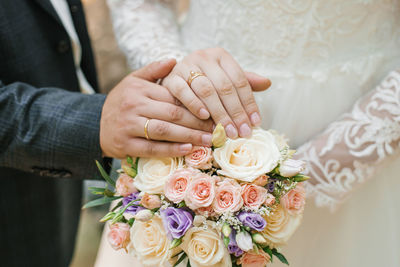 Newlywed couple holding rose bouquet. wedding rings on the hands of the bride and groom person