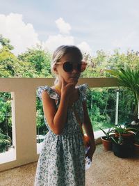 Woman wearing sunglasses standing by plants against sky