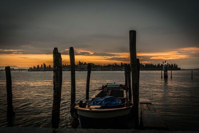 Sailboats moored on sea against sky during sunset