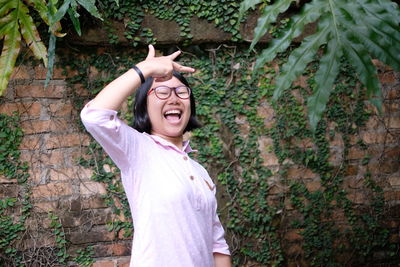 Woman gesturing against brick wall