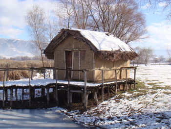 Built structure by frozen bare trees against sky