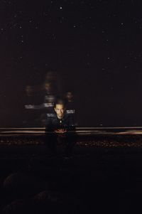 Digital composite image of woman sitting on railroad track at night