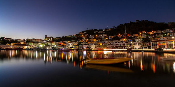 Boats moored in illuminated buildings against clear sky at night