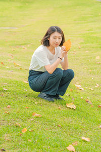 Side view of young woman sitting on grassy field