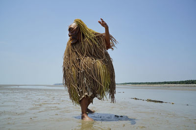 Rear view of man walking on beach against clear sky