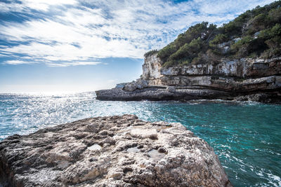 Scenic view of sea by cliff against sky