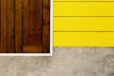 Close-up of yellow door on wooden wall of house