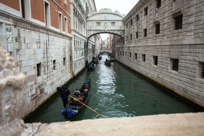 Man sailing boat on canal amidst buildings