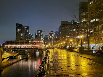 Illuminated bridge over river by buildings in city at night