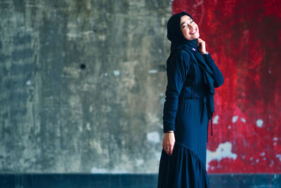 Beautiful indonesian woman wearing a black hijab against the rustic wall as a background