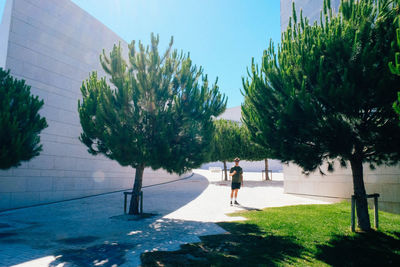 Woman walking on grass in city against clear sky