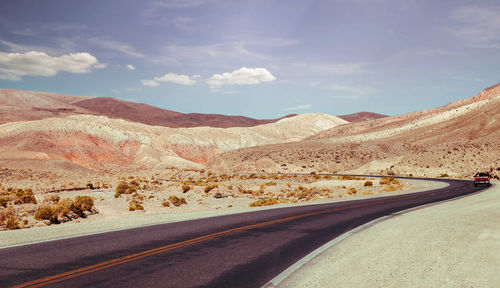 Road by mountains against sky