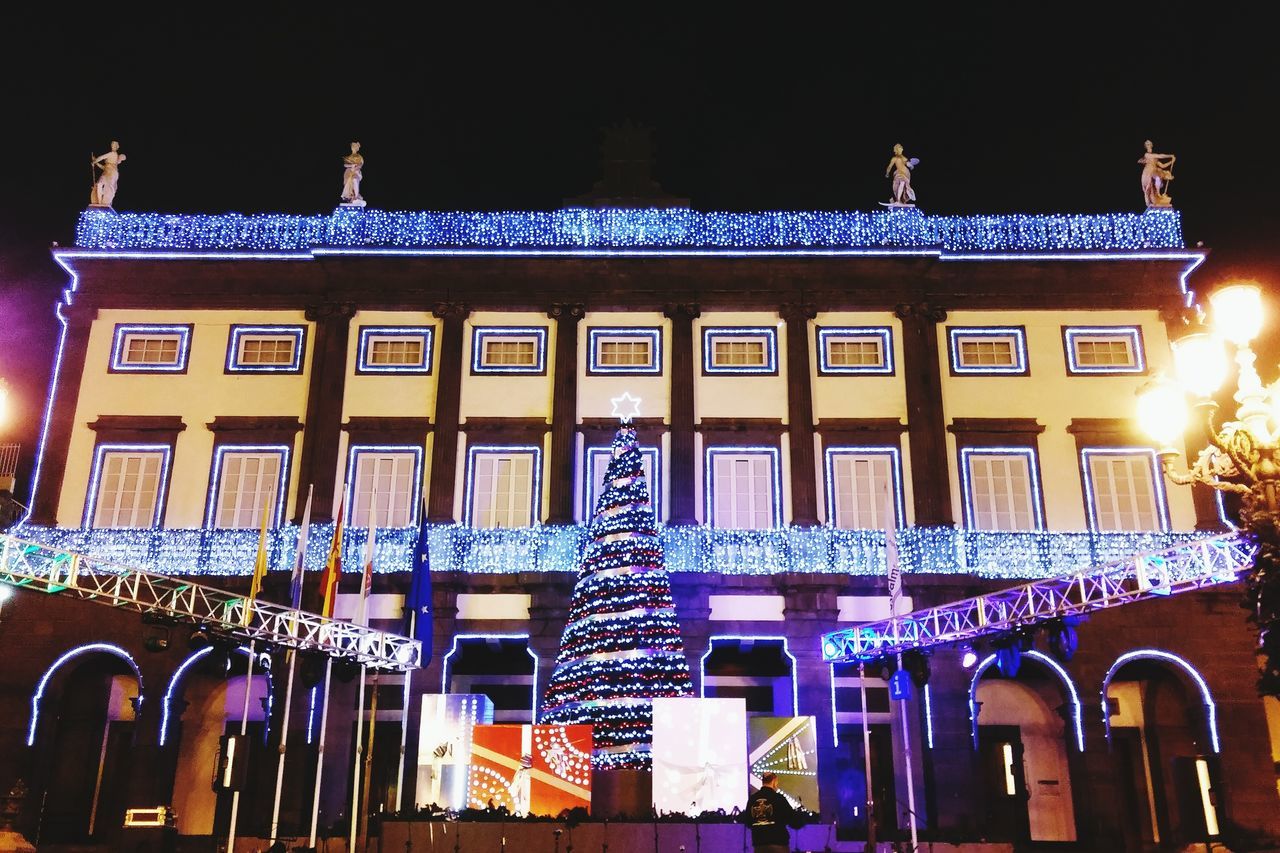 architecture, built structure, text, building exterior, night, illuminated, western script, clear sky, low angle view, non-western script, communication, facade, city, lighting equipment, window, outdoors, building, blue, no people, street light