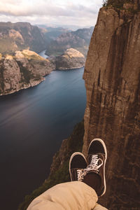 Person cross legged at edge of cliff with a fjords view in norway