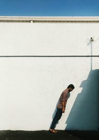 Shadow of man standing on wall against clear sky