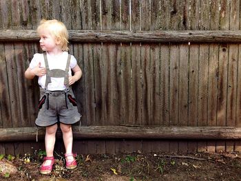 Cute girl standing against wooden fence