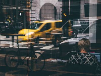 Rear view of man sitting on table at cafe in city