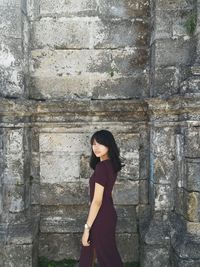 Full length of woman standing against wall