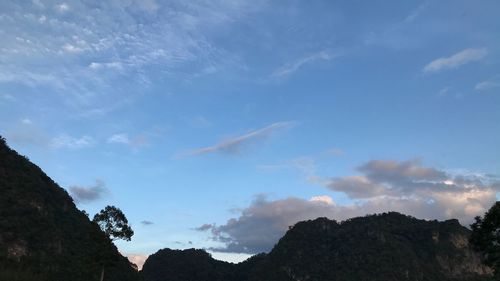 Low angle view of silhouette mountains against blue sky