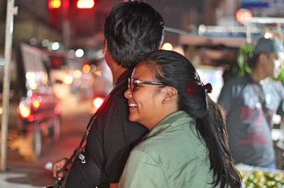 Close-up of smiling woman with father in illuminated city at night