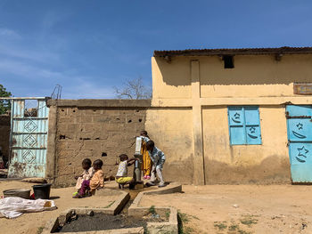 People sitting on wall against blue sky