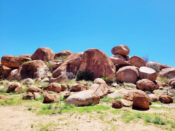Rocks on field against clear blue sky