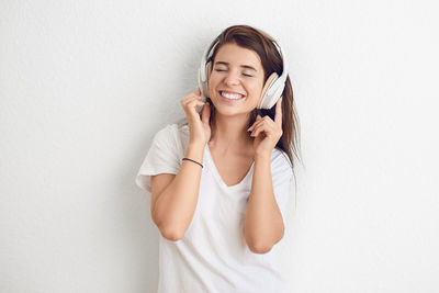 Portrait of a smiling young woman standing against wall