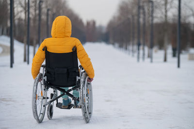 Rear view of woman son wheelchair during winter