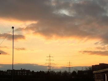 Silhouette electricity pylon against sky during sunset