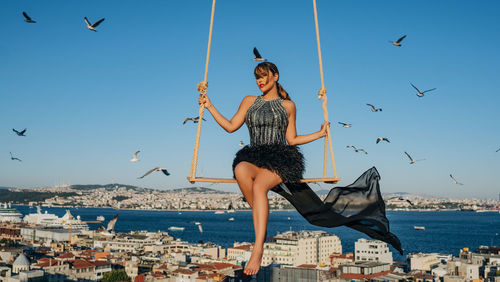 Low angle view of woman jumping against sky 